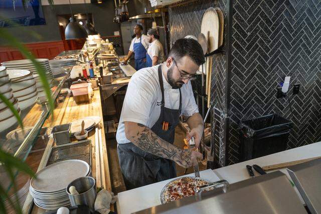 Zach Schechtman, Good Neighbor’s executive chef, grates cheese over a pepperoni pizza at the Sacramento restaurant on Jan. 29.